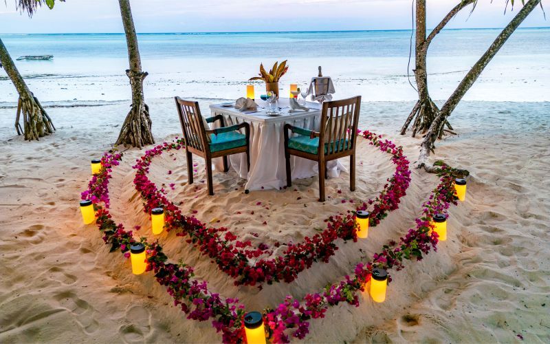 A romantic beachside dinner set under the stars, with the sound of waves, soft candlelight, and a serene atmosphere perfect for creating unforgettable moments with your loved one.